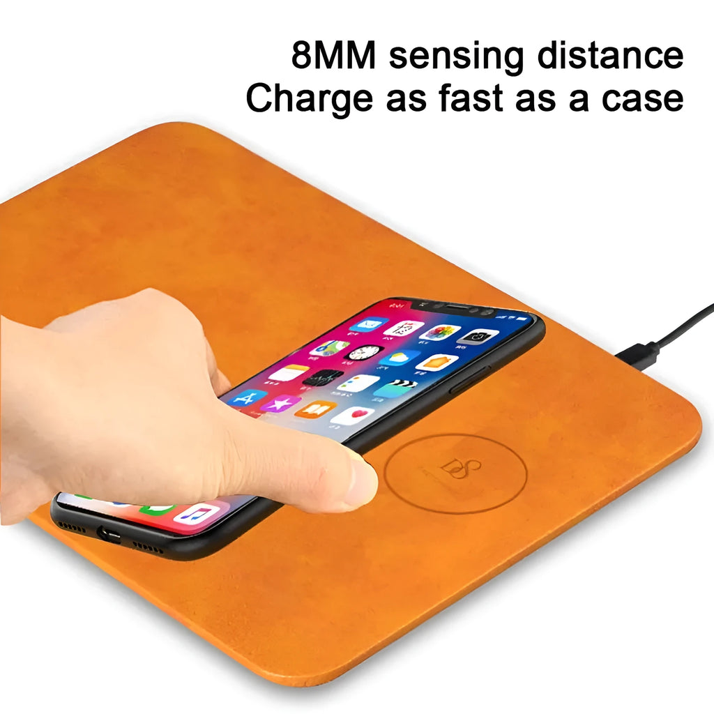 Brown leather-texture wireless charging mouse pad with a phone placed on it charging, on a wooden desk.