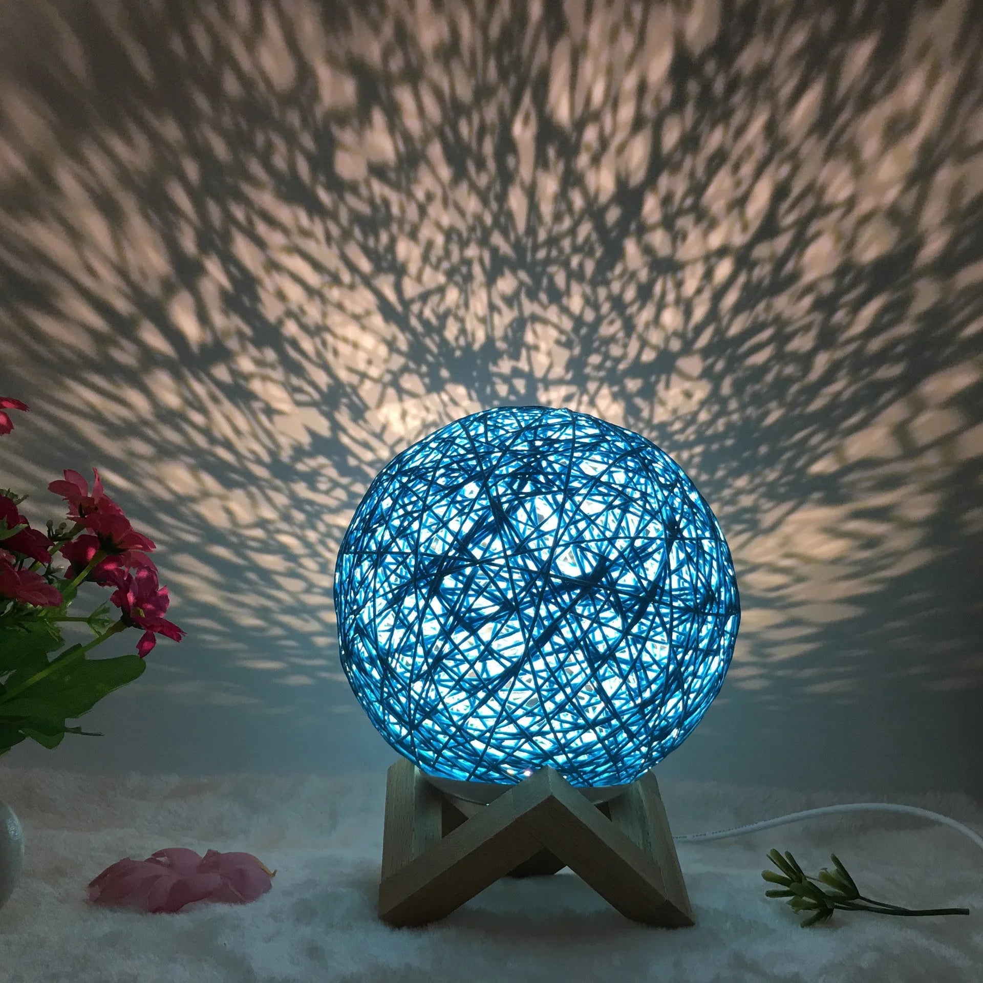 Rattan ball table lamp with woven shade and warm LED lighting on wooden surface