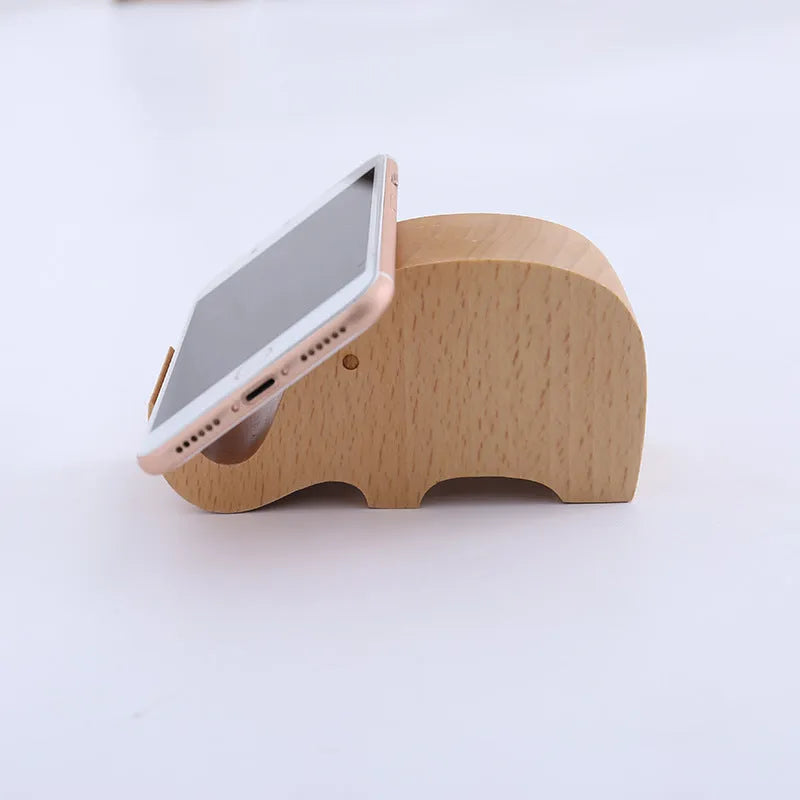 Solid beech wood phone stand with a decorative resin puppy figurine, holding a mobile phone at an angle with a charging cable threaded through the back.