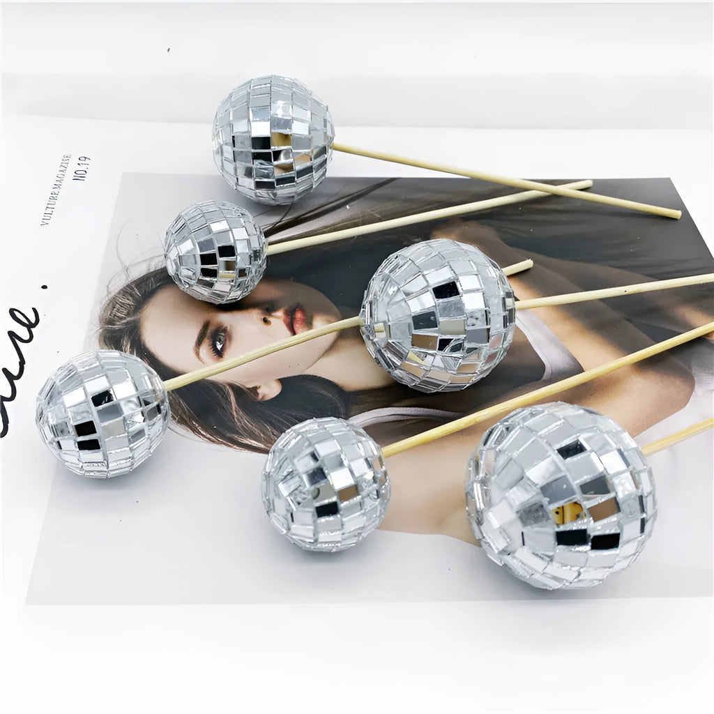 Glass disco ball cake decoration with wooden stick in various sizes on a cake