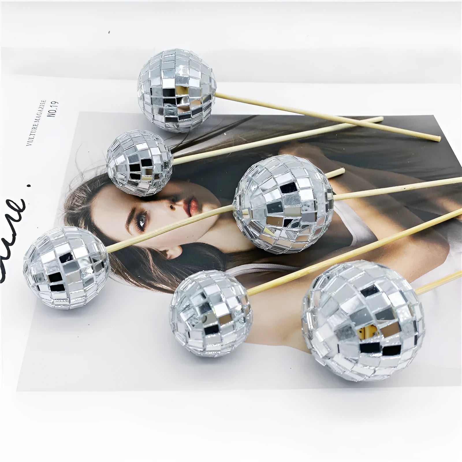 Glass disco ball cake decoration with wooden stick in various sizes on a cake