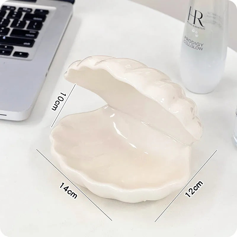 White and pink porcelain shell-shaped tray with integrated yellow LED night light on a wooden table.