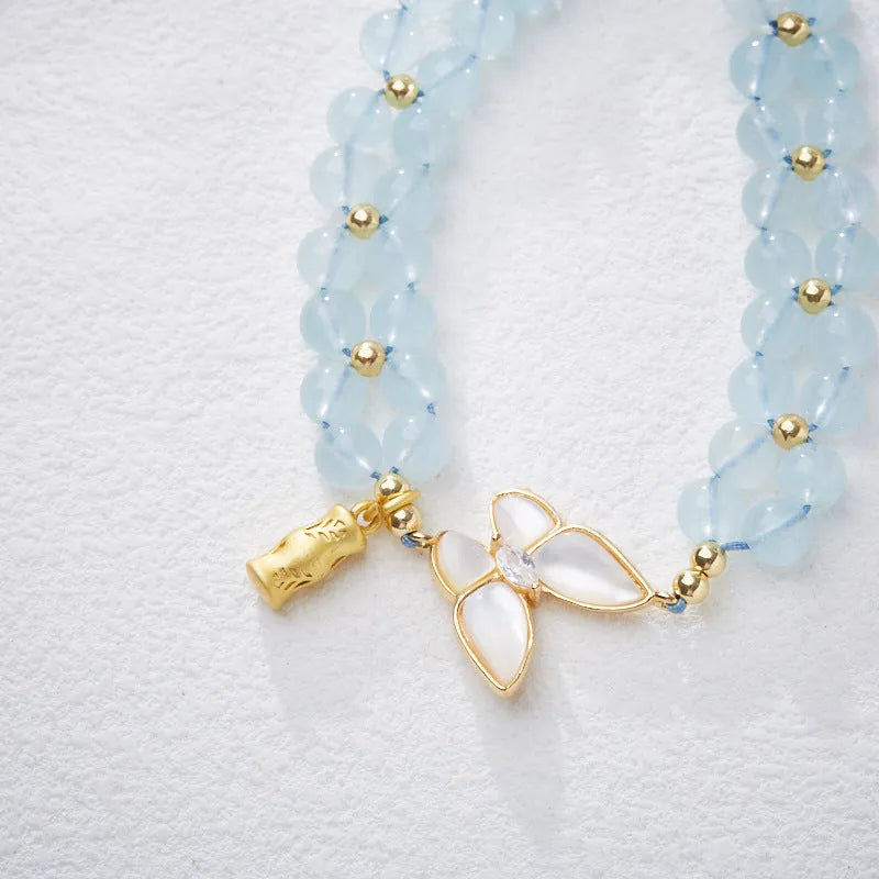 Close-up of a handmade women's woven bracelet with 6mm butterfly design in aquamarine gemstone beads.