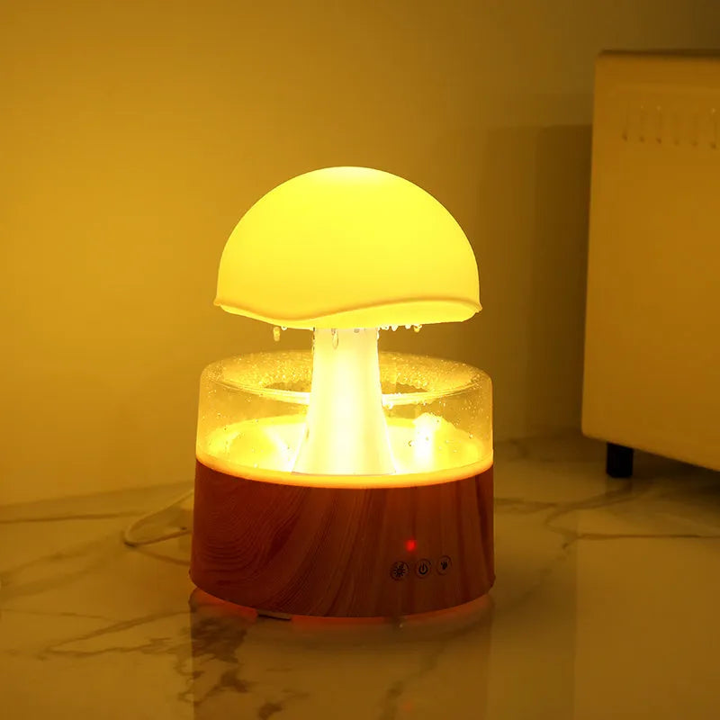 White plastic rain cloud humidifier with mist and coloured night light on a wooden surface