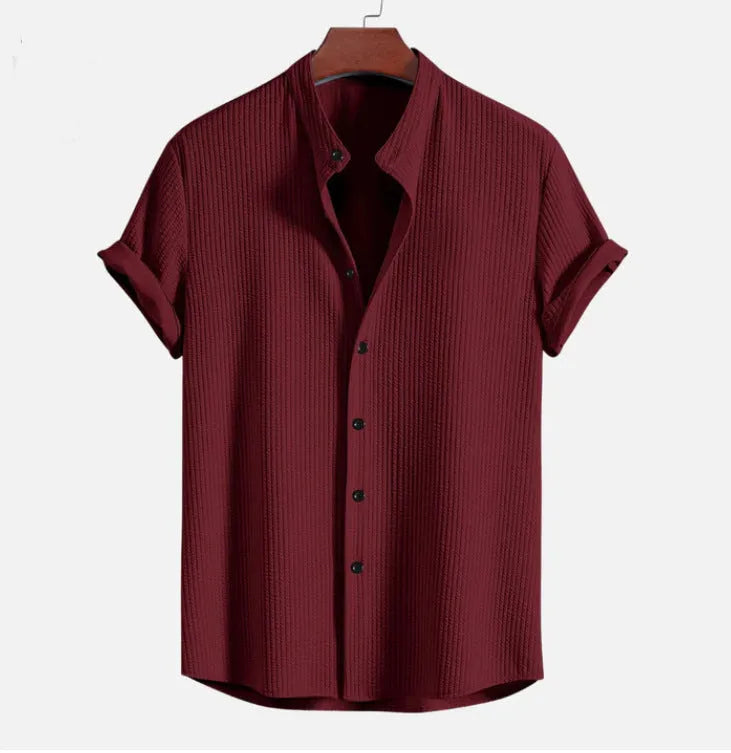 A man wearing a loose-fitting short sleeve casual shirt in a solid colour.