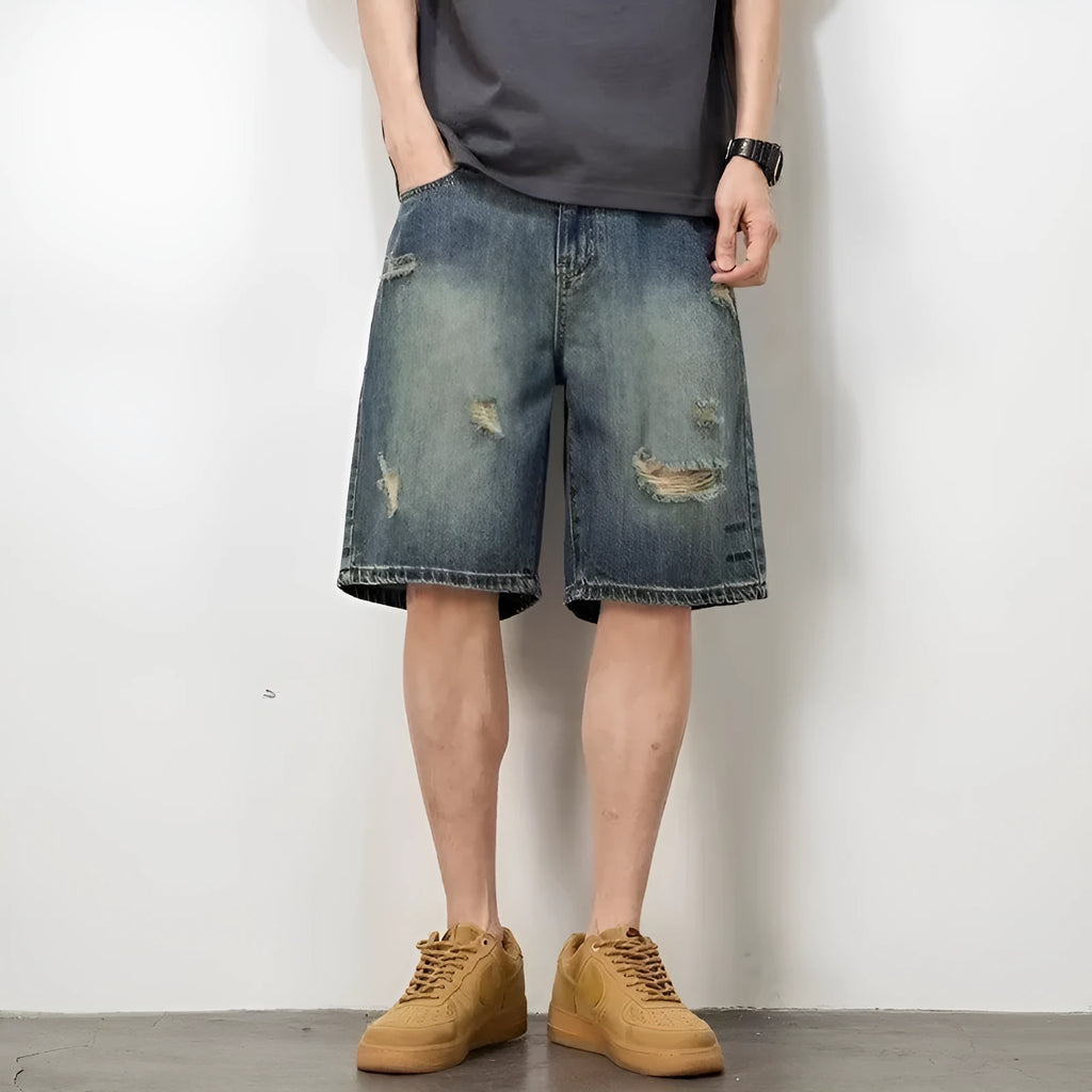 Man wearing blue retro loose hole distressed denim shorts with a straight leg cut