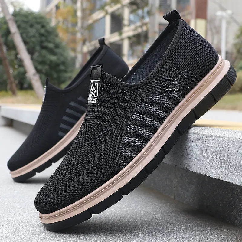Men's slip-on casual sneakers with black mesh upper, low top, flat heel, and round toe.