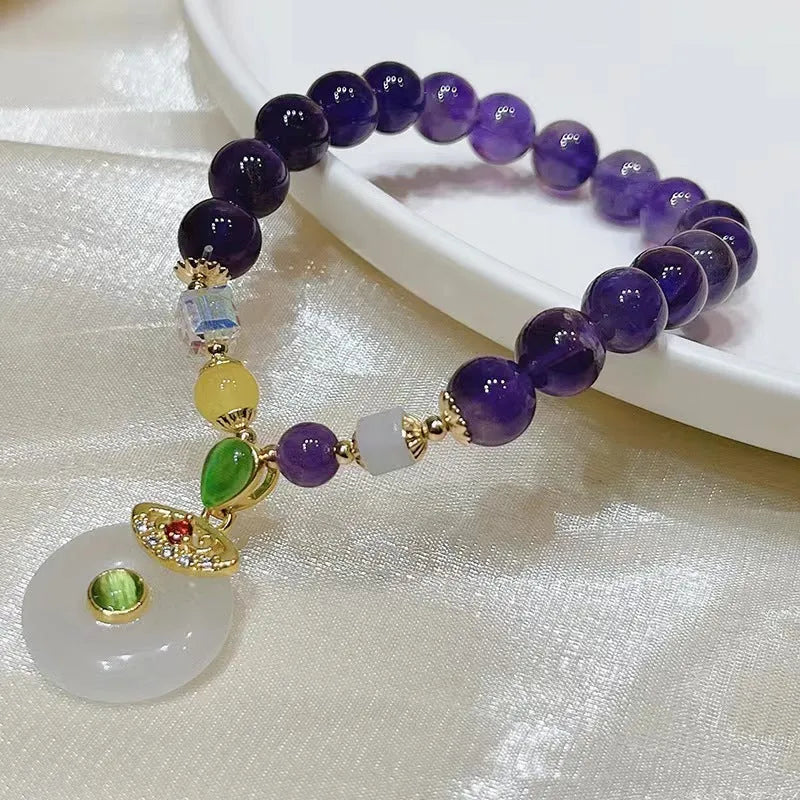 Purple amethyst crystal bracelet with money bag charm and peace buckle on woman's wrist