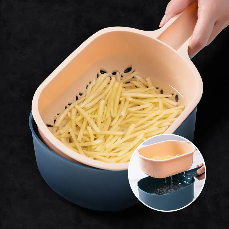 Dark blue scoop vegetable cutter with four stainless steel blades, hand guard and drain basket on a kitchen worktop