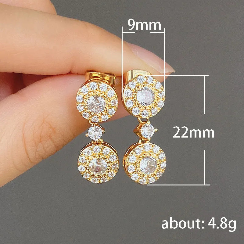 Women's gold copper round zircon stud earrings on a light background