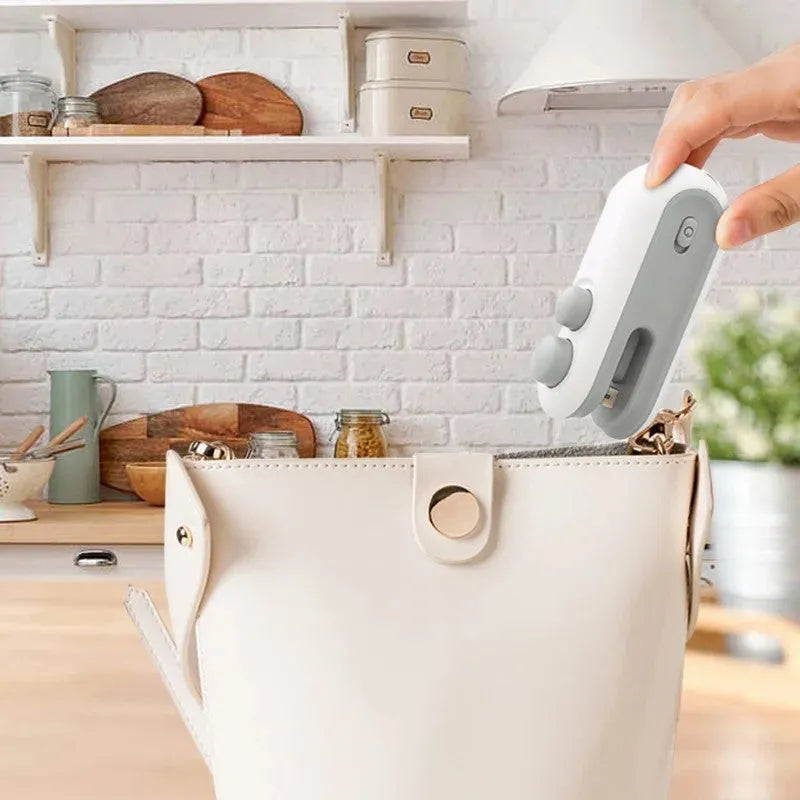 Blue and white handheld USB rechargeable heat sealer with built-in cutter for sealing food bags.