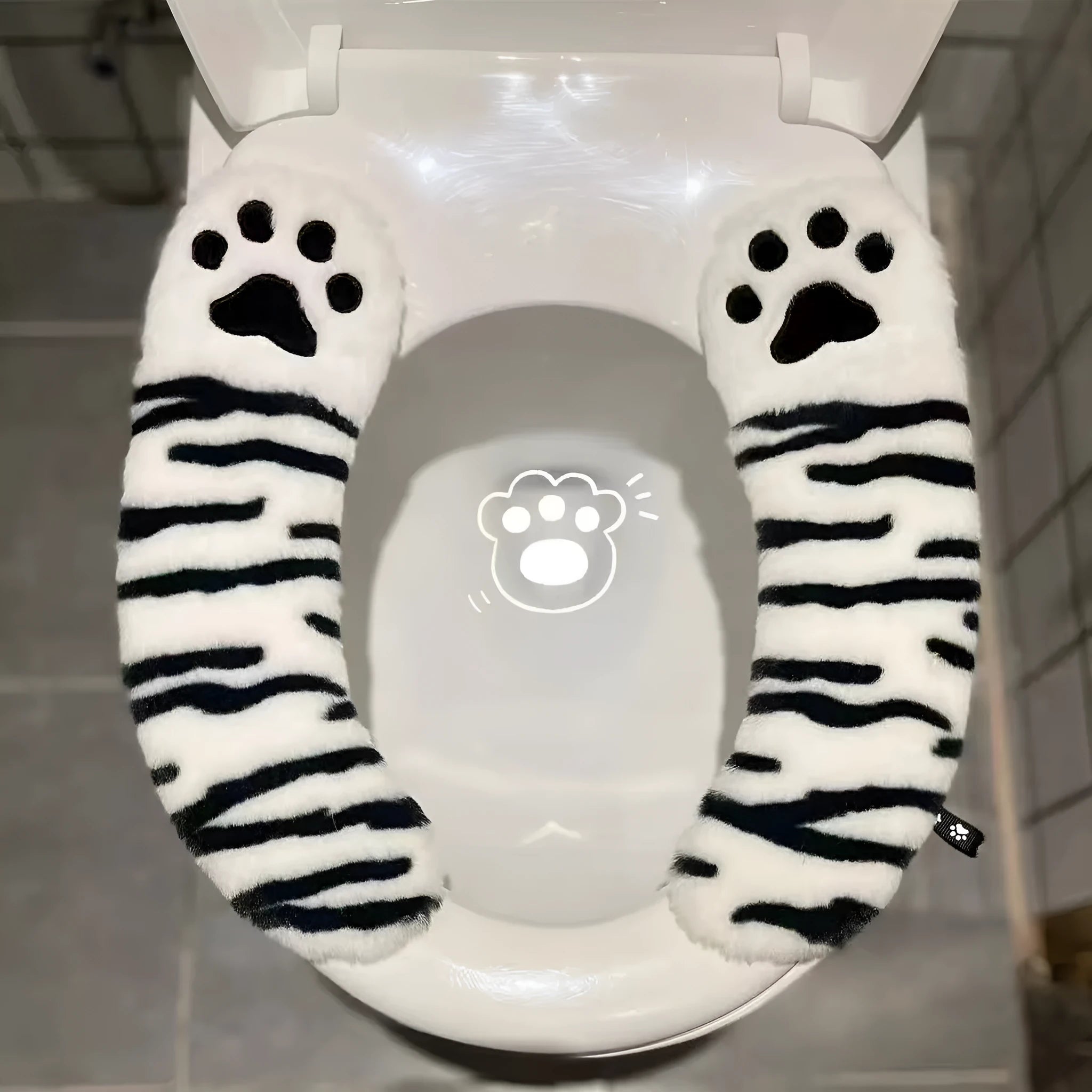 Plush toilet seat cushion with adhesive Velcro fastener in black and white stripes for bathroom use