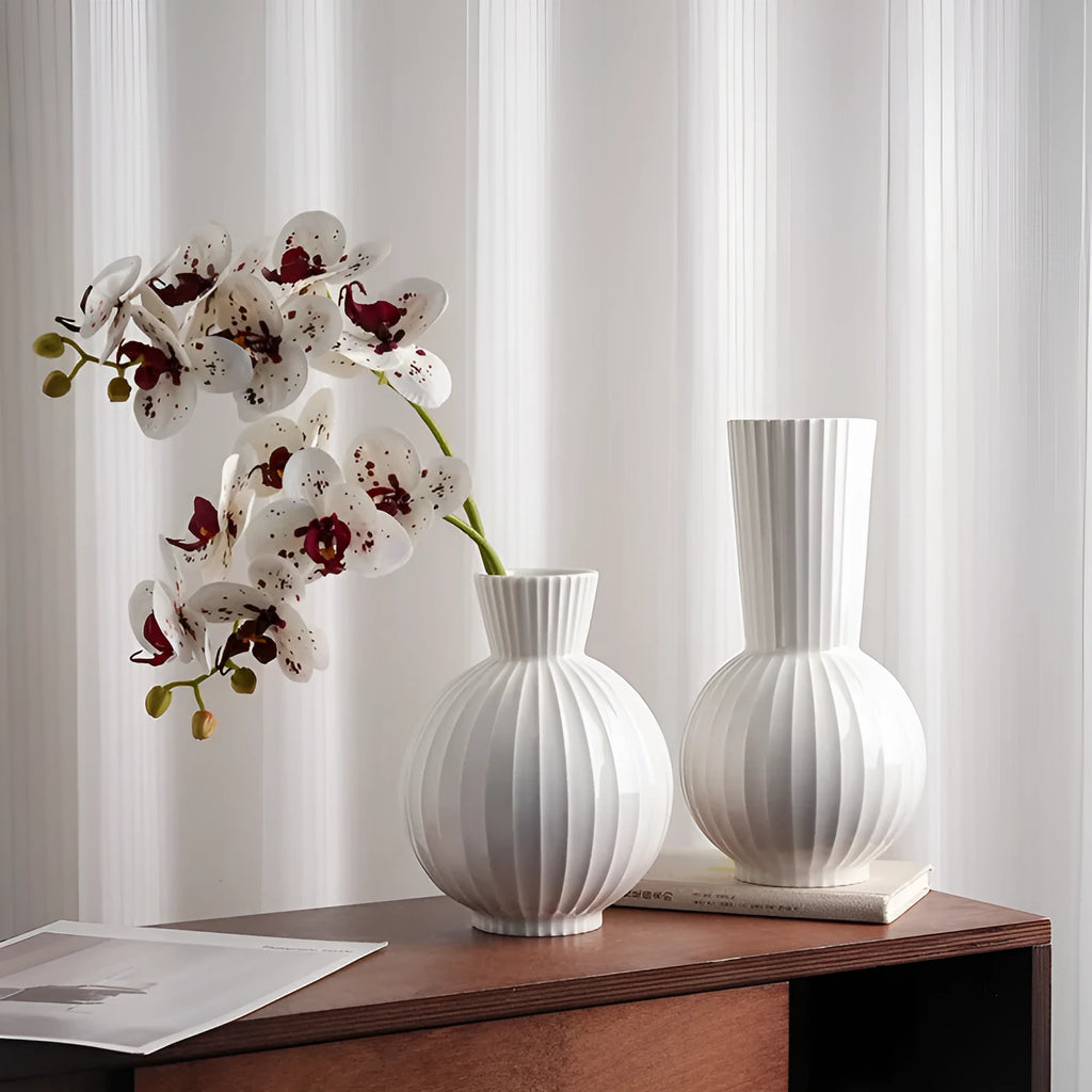 White ceramic ball vase with blue stripes, a silk blue orchid, on a wooden table.