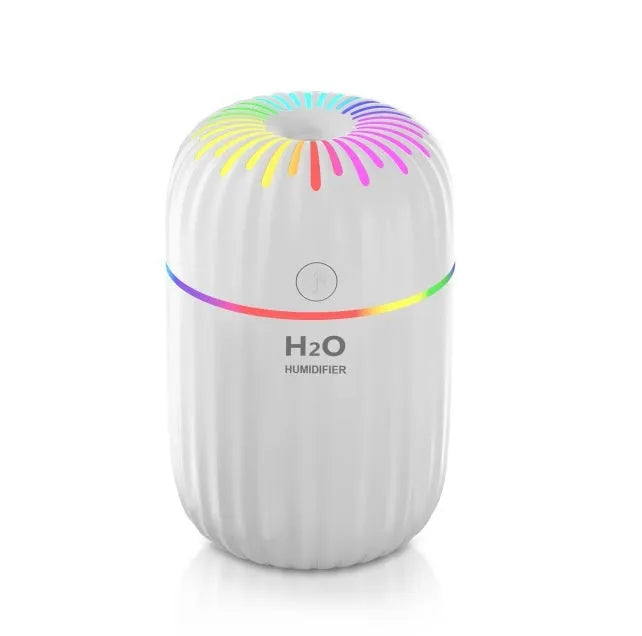 Small white USB desktop humidifier with water tank on a wooden desk.