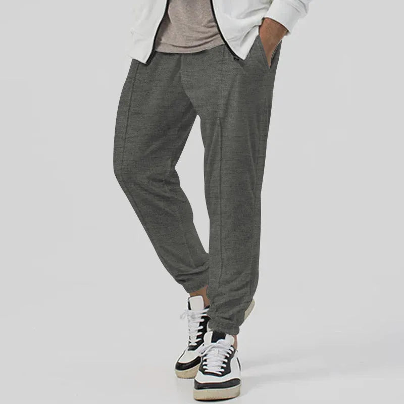 Men's grey straight-leg track sweatpants with a mid-waist, showcasing a relaxed fit and casual style.