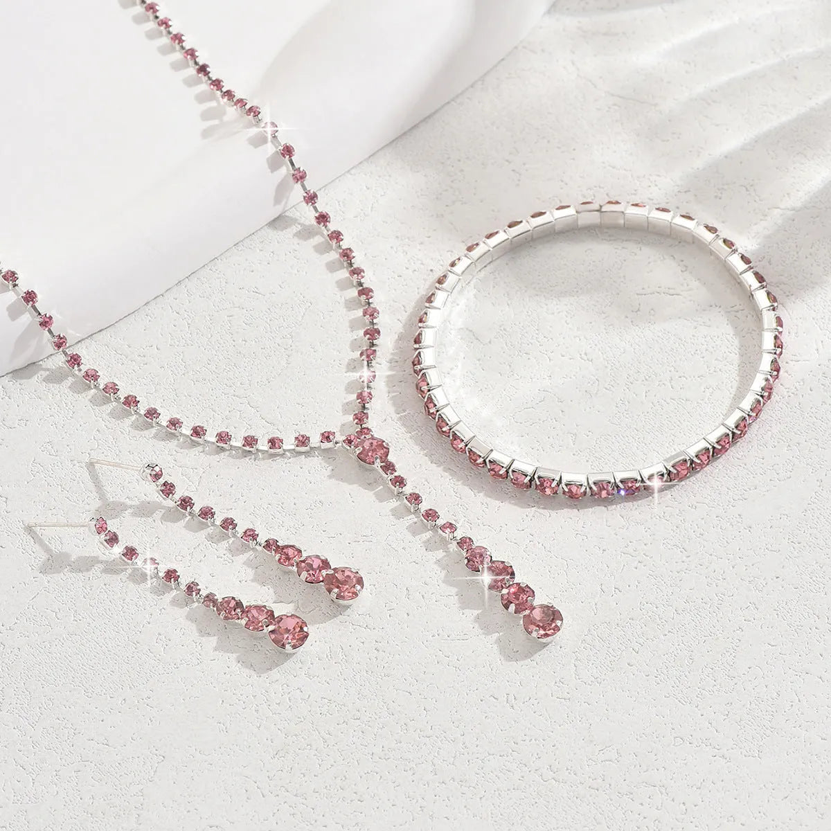 Women's three-piece bridal jewellery set showing earrings, necklace and bracelet with rhinestone heart-shaped pendant