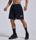 Man modelling black loose-fit cropped sports shorts with letter detail and an elastic waistband.
