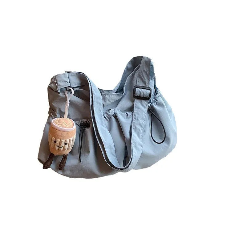 Soft foldable polyester crossbody bag in beige colour showing split pocket and crossbody strap.