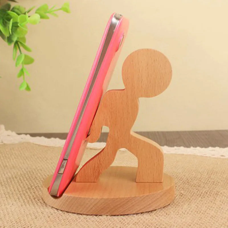 Solid beech wood phone stand with a decorative resin puppy figurine, holding a mobile phone at an angle with a charging cable threaded through the back.