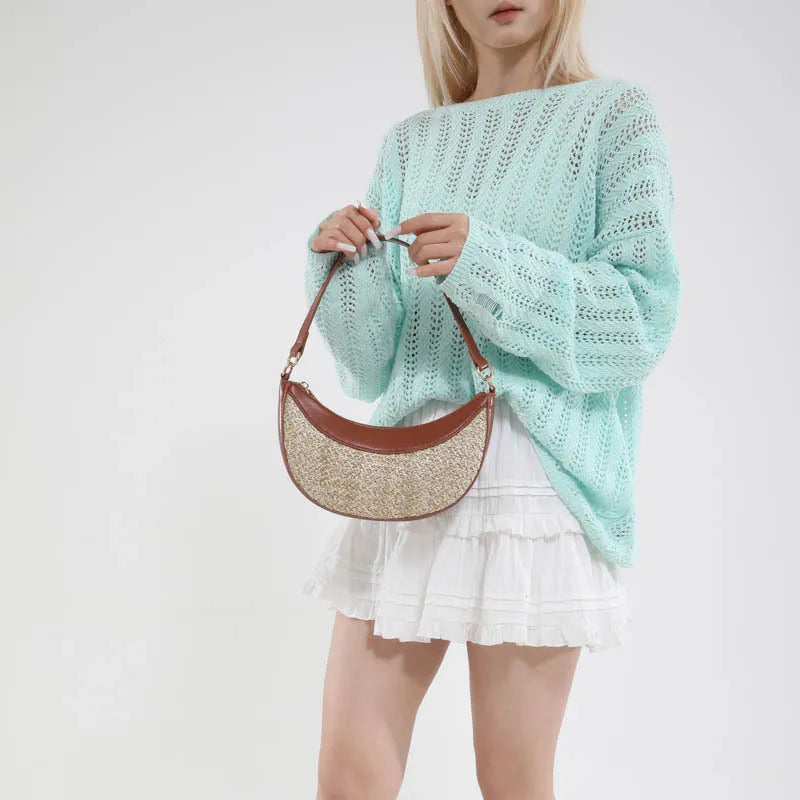Hard structured straw dumpling shaped women's crossbody shoulder bag in black, shown with interior phone pocket.