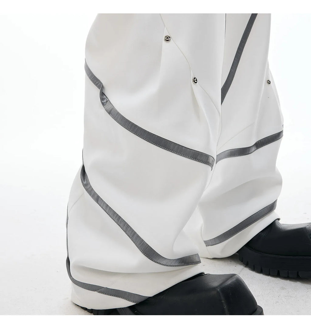 Men's black trousers with metal rivet pleats and a three-dimensional tailored cut.