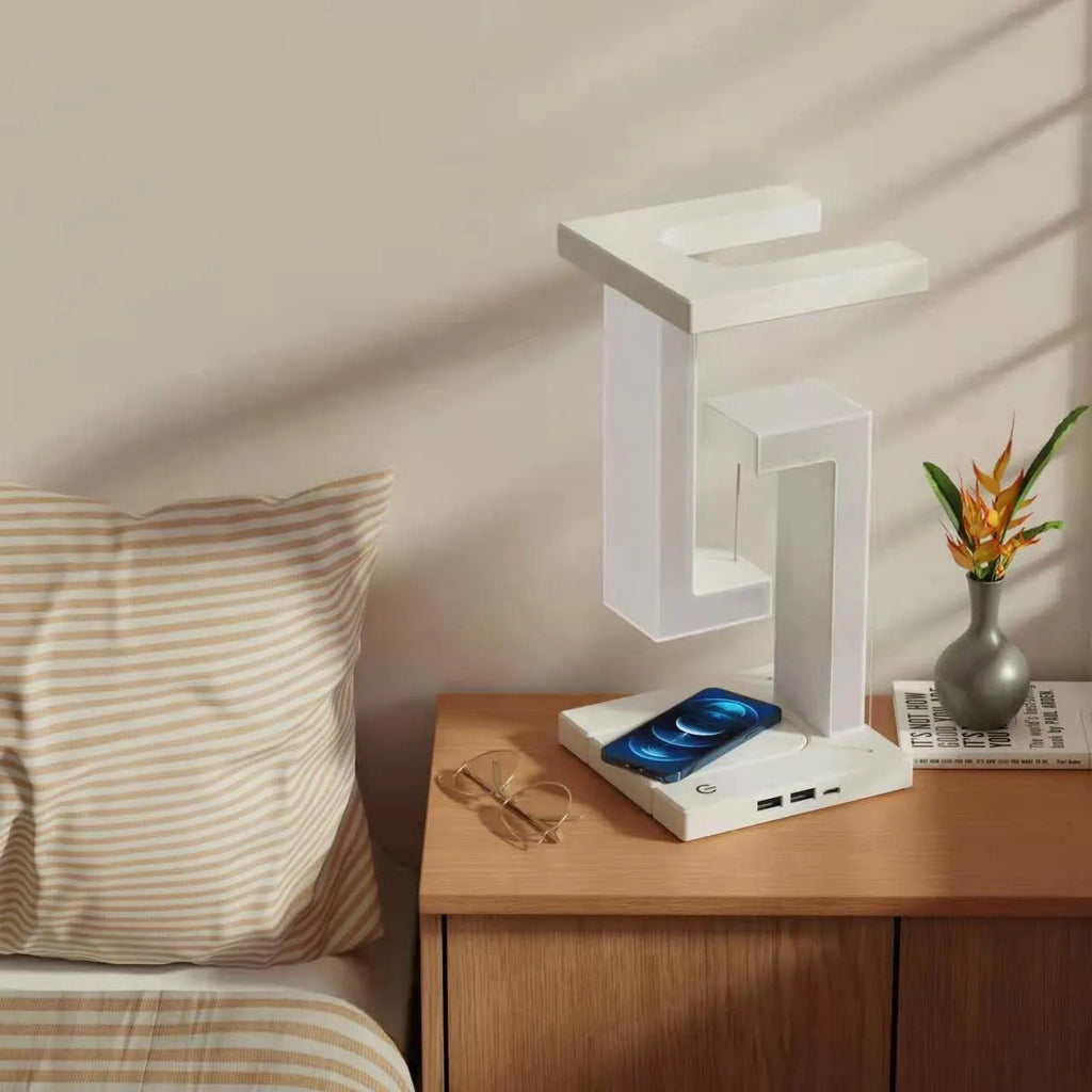White magnetic suspension table lamp with wireless charging base, floating shade, and foldable bracket on a desk