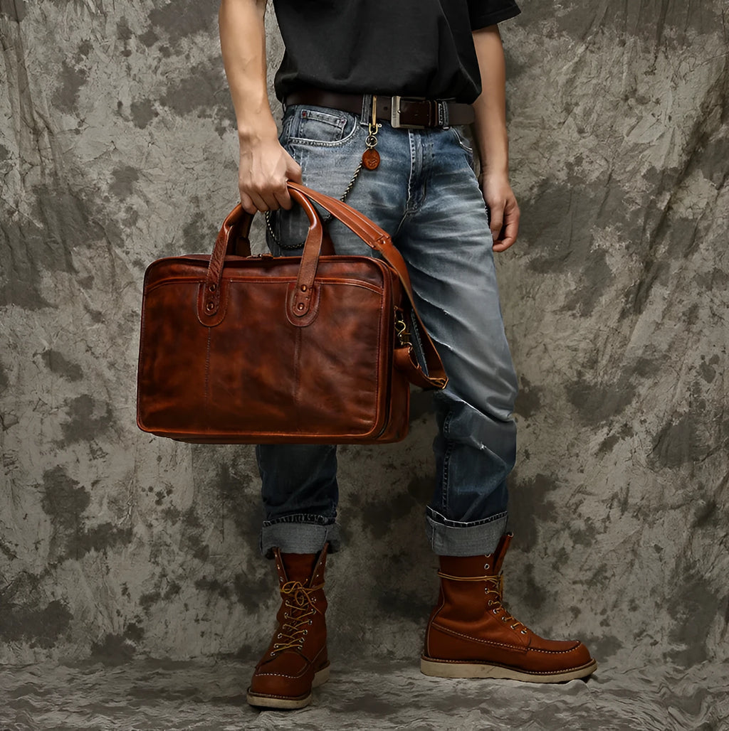 Men's vintage brown leather briefcase open to show internal laptop and camera pockets.