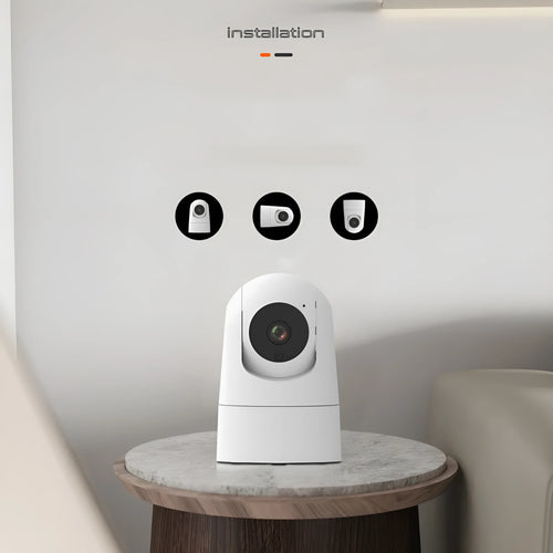White indoor security camera with lens on a circular motorised base, showing compact size for shelf placement.