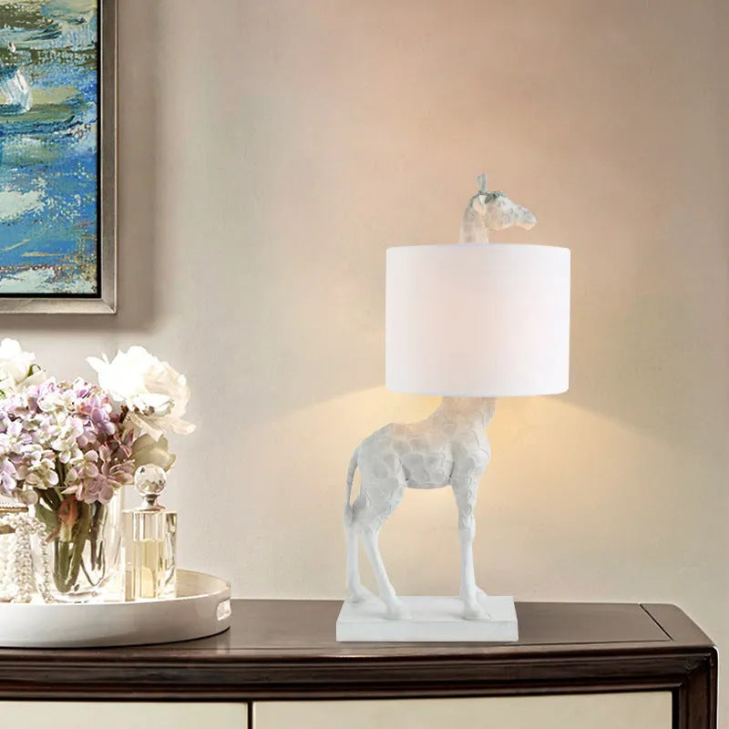 Giraffe table lamp with resin base and cloth shade, 66cm high, in white finish on a bedside table