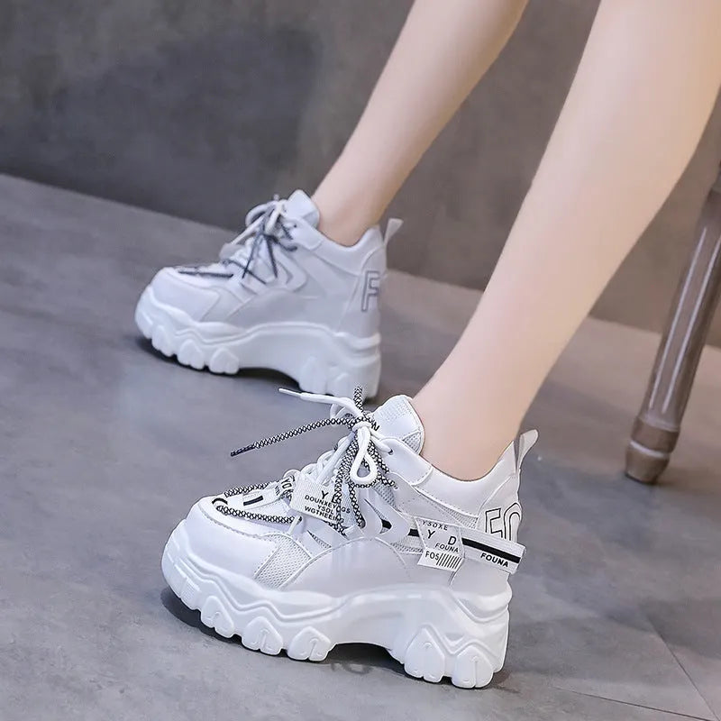 Women's white and black platform sports shoes with cross strap and rubber sole.
