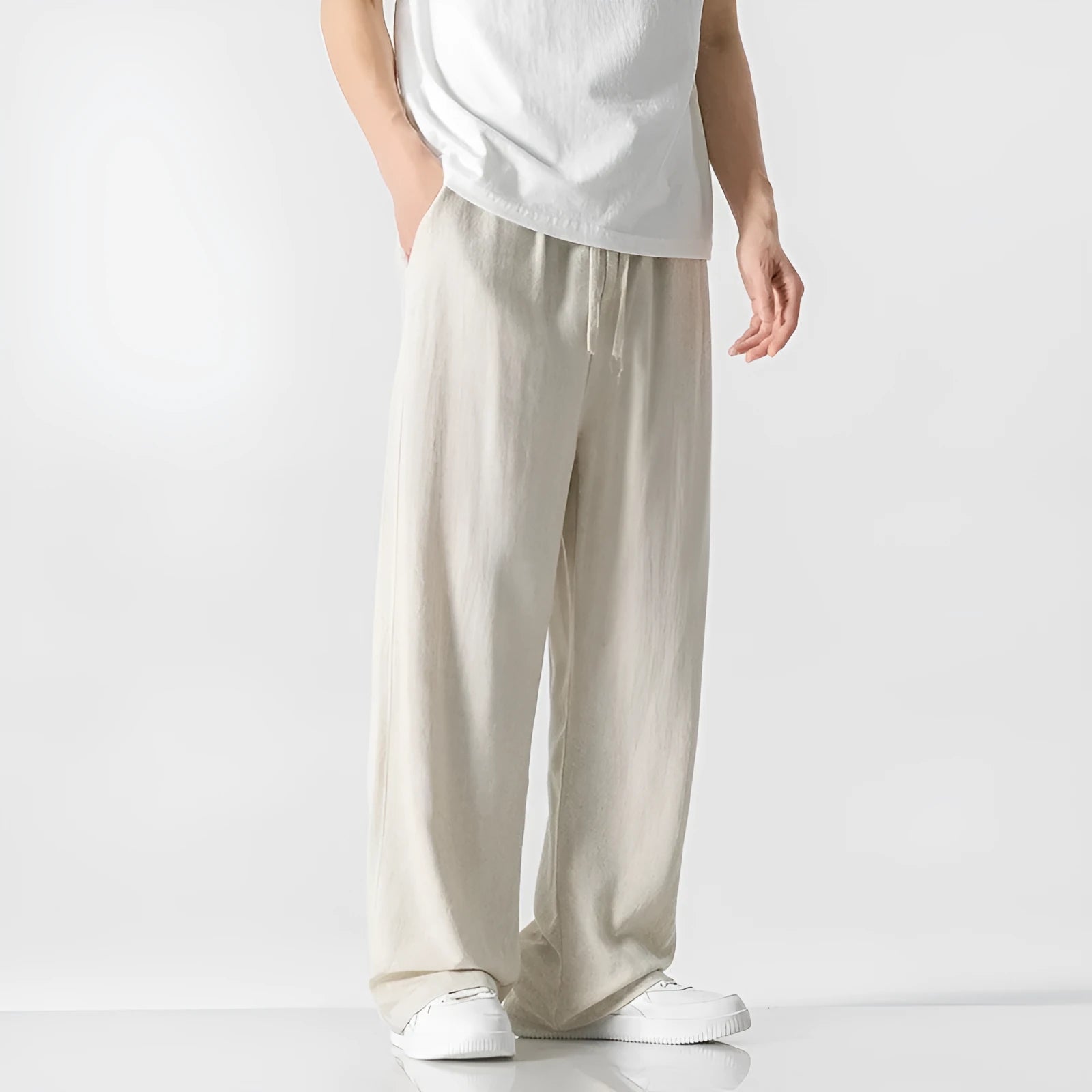 Man wearing beige cropped straight-leg bamboo fibre trousers with a drawstring waist on a summer day.
