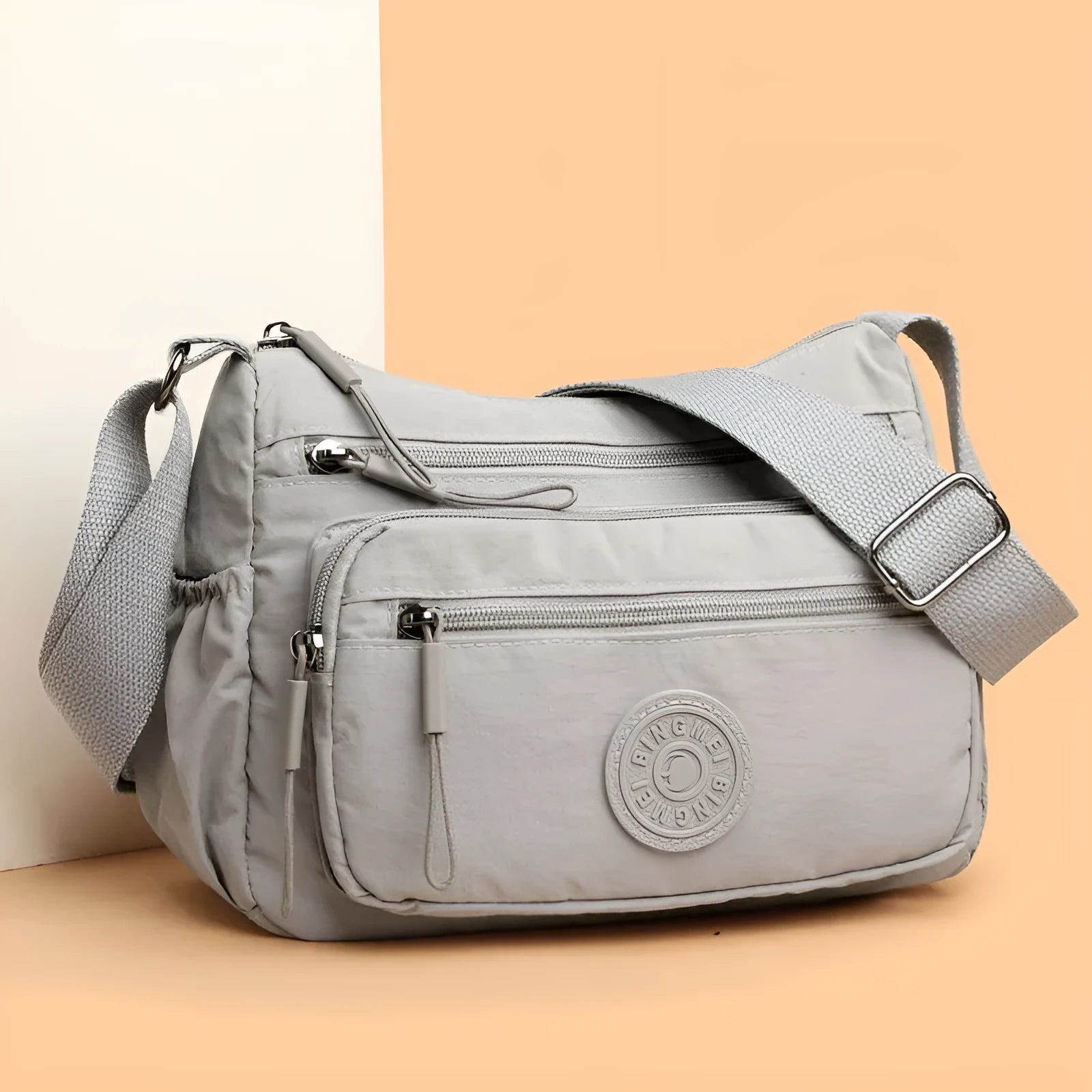 Soft nylon crossbody bag in black, grey, or red with a single shoulder strap and water-repellent finish.