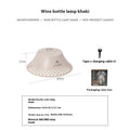 Beige wine bottle-shaped camping lantern with LED light on a wooden surface outdoors.