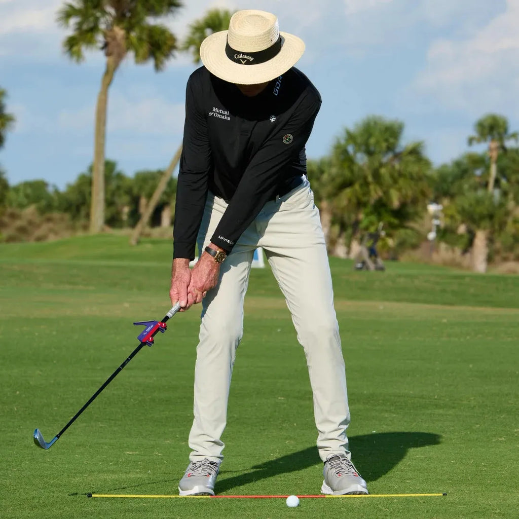 Plastic golf swing plane simulator trainer on a practice mat.