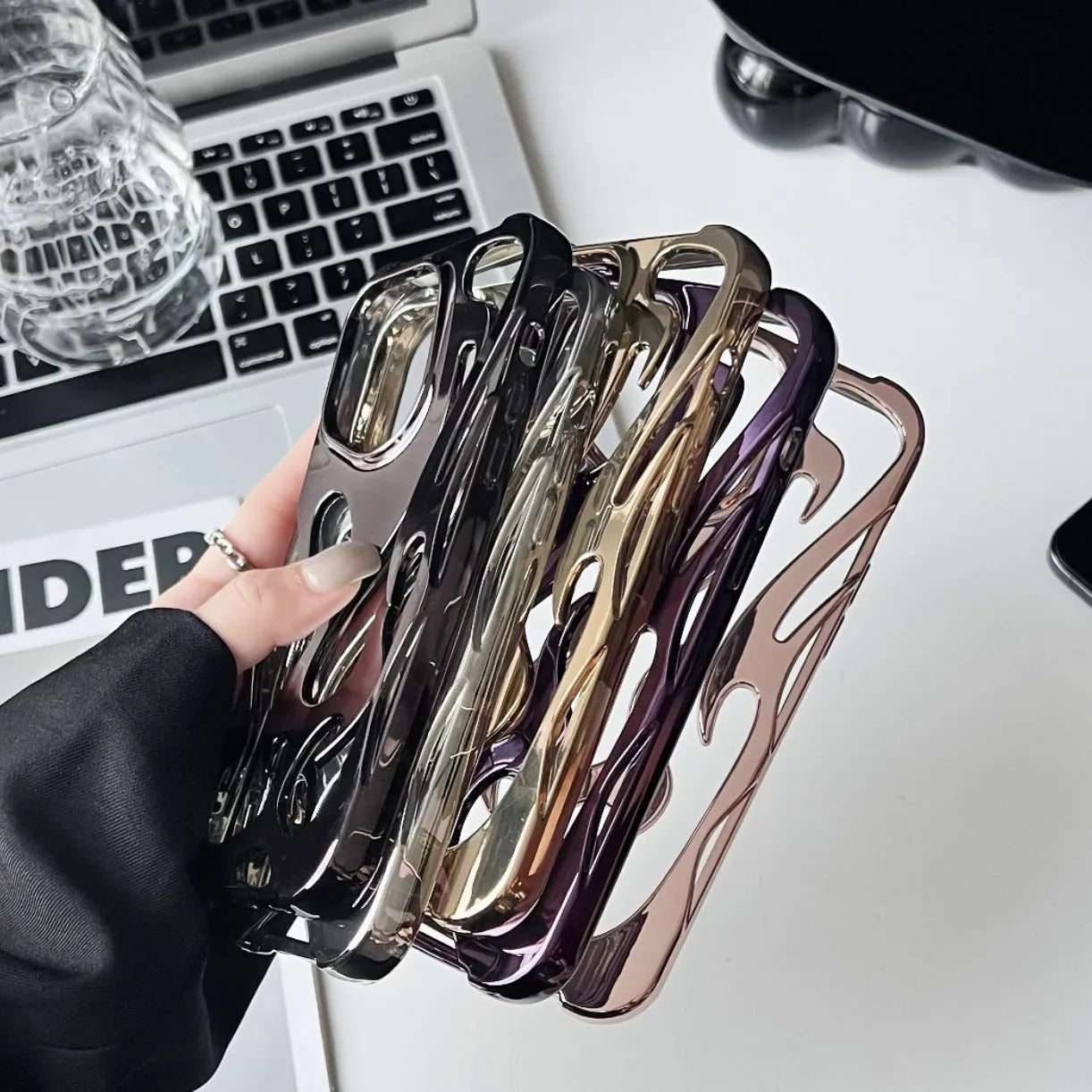 Electroplated hollow flame pattern TPU phone case for iPhone on a table, showing silver metallic finish and ventilation design.