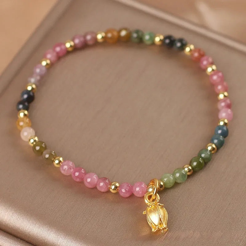 Natural tourmaline bead anklet for women with a silver flower charm on an ankle.
