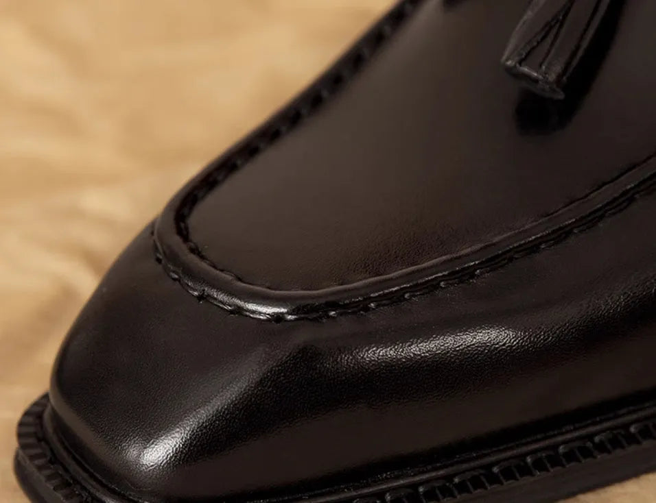 Men's black genuine leather loafers with a fringed detail and slip-on design.