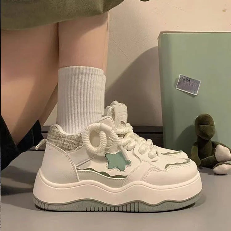 Women's green patent leather-look platform sneaker with round toe and white lace-up front, on a white background.