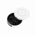 Small black semi-in-ear wireless headphones with their wireless charging case on a table.