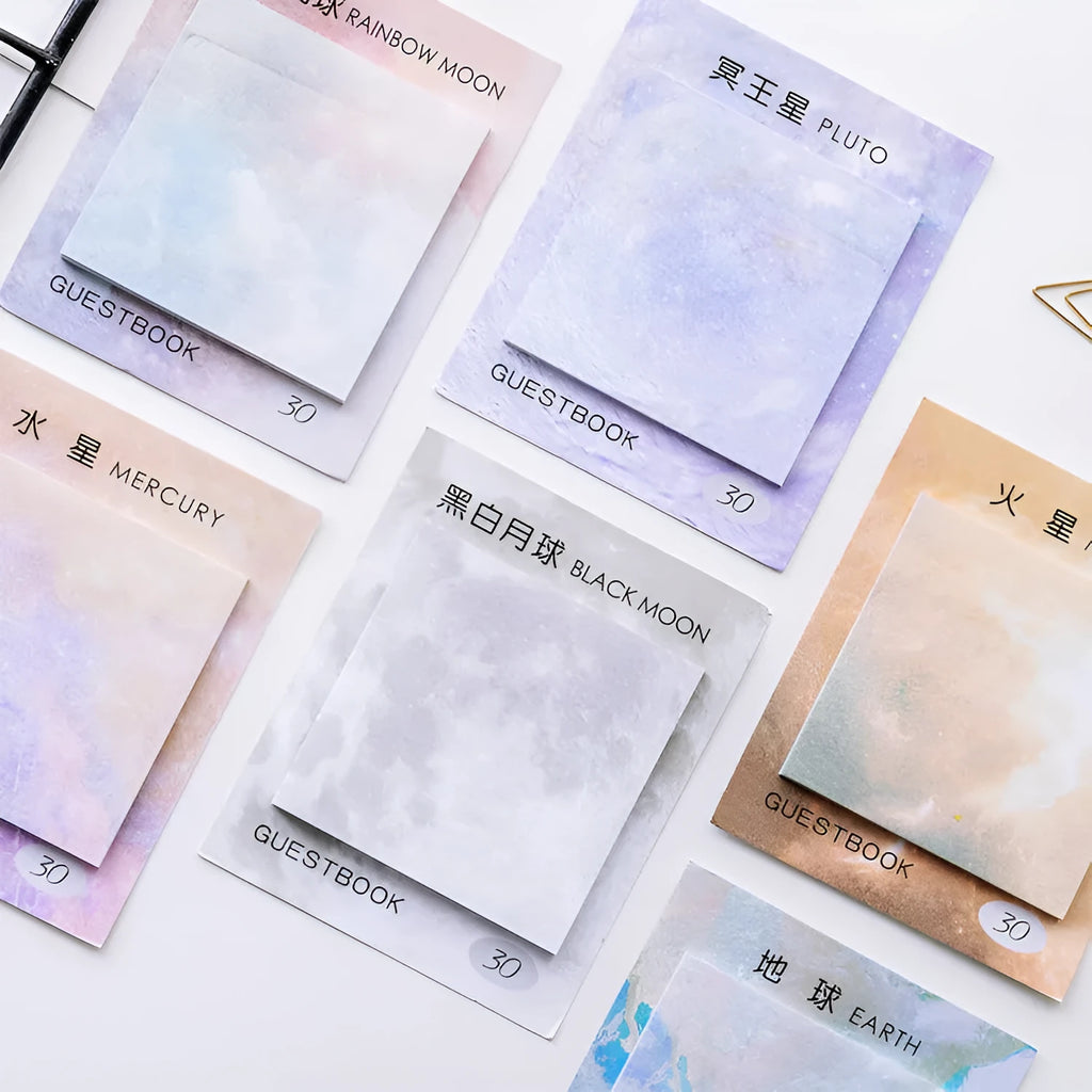 Square sticky notes notepad open to show planet oil painting designs including Earth and Rainbow Moon.