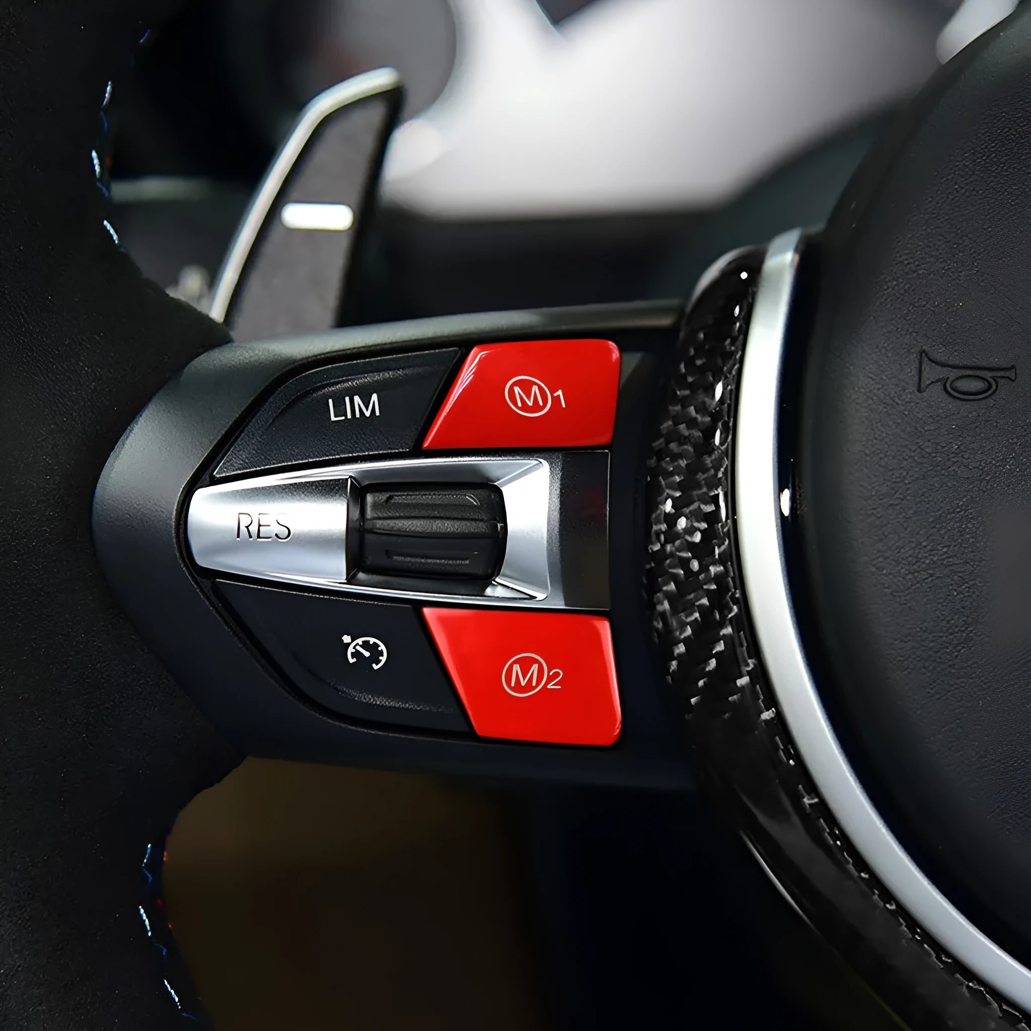 Pair of red and blue BMW M1 and M2 steering wheel mode buttons on a white background.