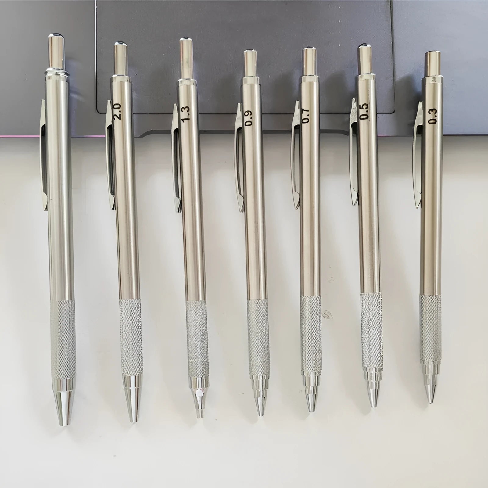 Metal automatic mechanical pencil showing six compatible lead sizes from 0.3mm to 2.0mm
