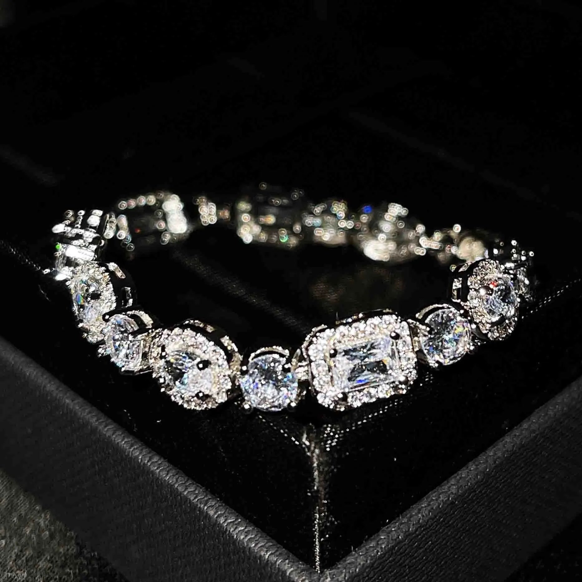 Women's geometric silver bracelet with inlaid white zircon stones on a wrist, showing adjustable clasp.