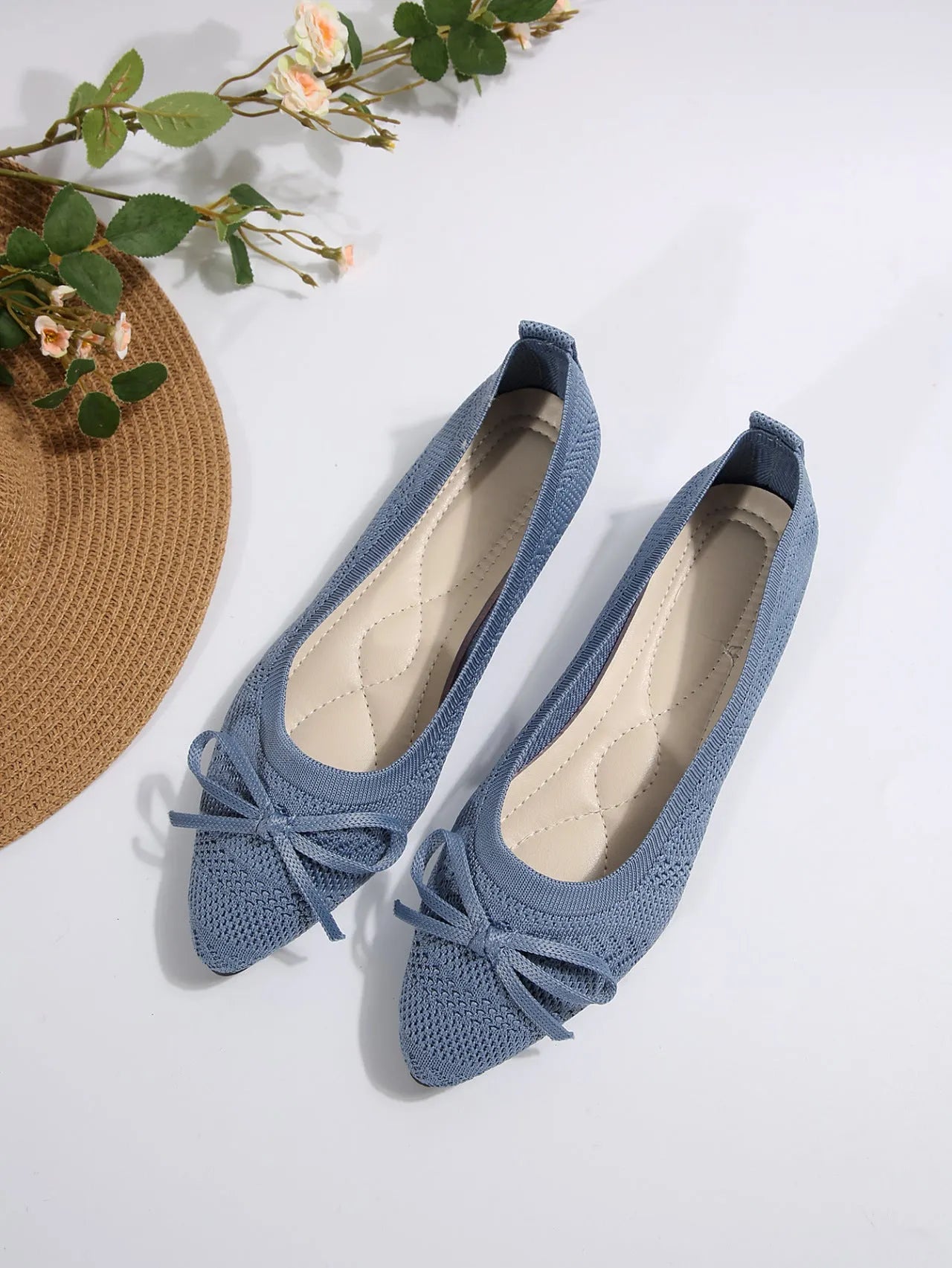 Women's blue knitted flat loafer with bow detail on pointed toe, showing rubber sole
