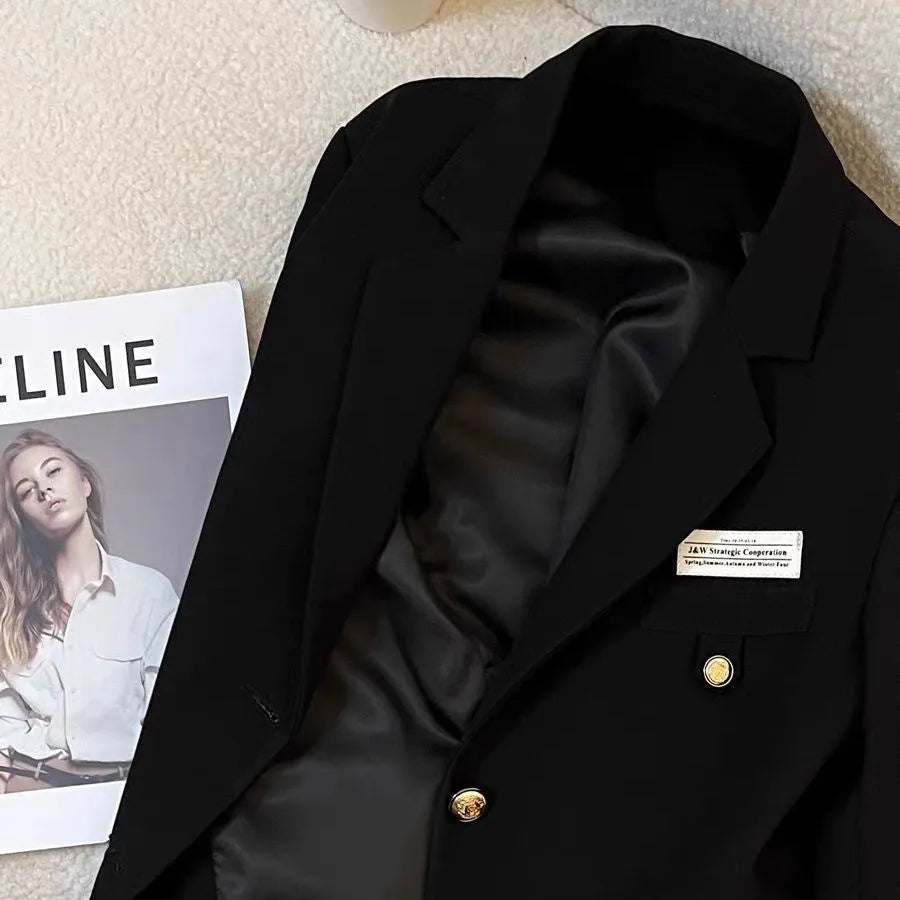 Women's black short suit coat with loose fit, long sleeves, and pocket details