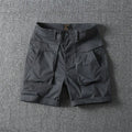 Men's straight-leg cotton cargo shorts in khaki with multiple pockets, shown on a model for summer street style.