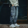 Blue men's loose straight-leg stretch denim trousers on a hanger, showing zip fly placket detail.