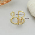 Gold-coloured adjustable open ring with an asymmetric U-shaped design on a finger.