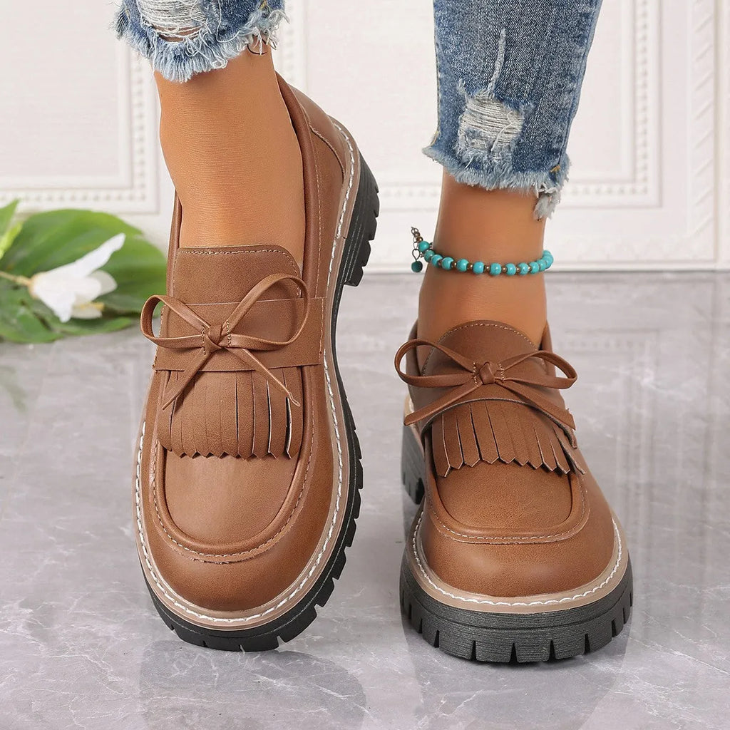 Women's black plus size loafers with a bowknot, tassel, and chunky rubber sole.