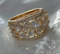 Women's hollow round fashion ring in gold and platinum finishes with blue and white stone accents.